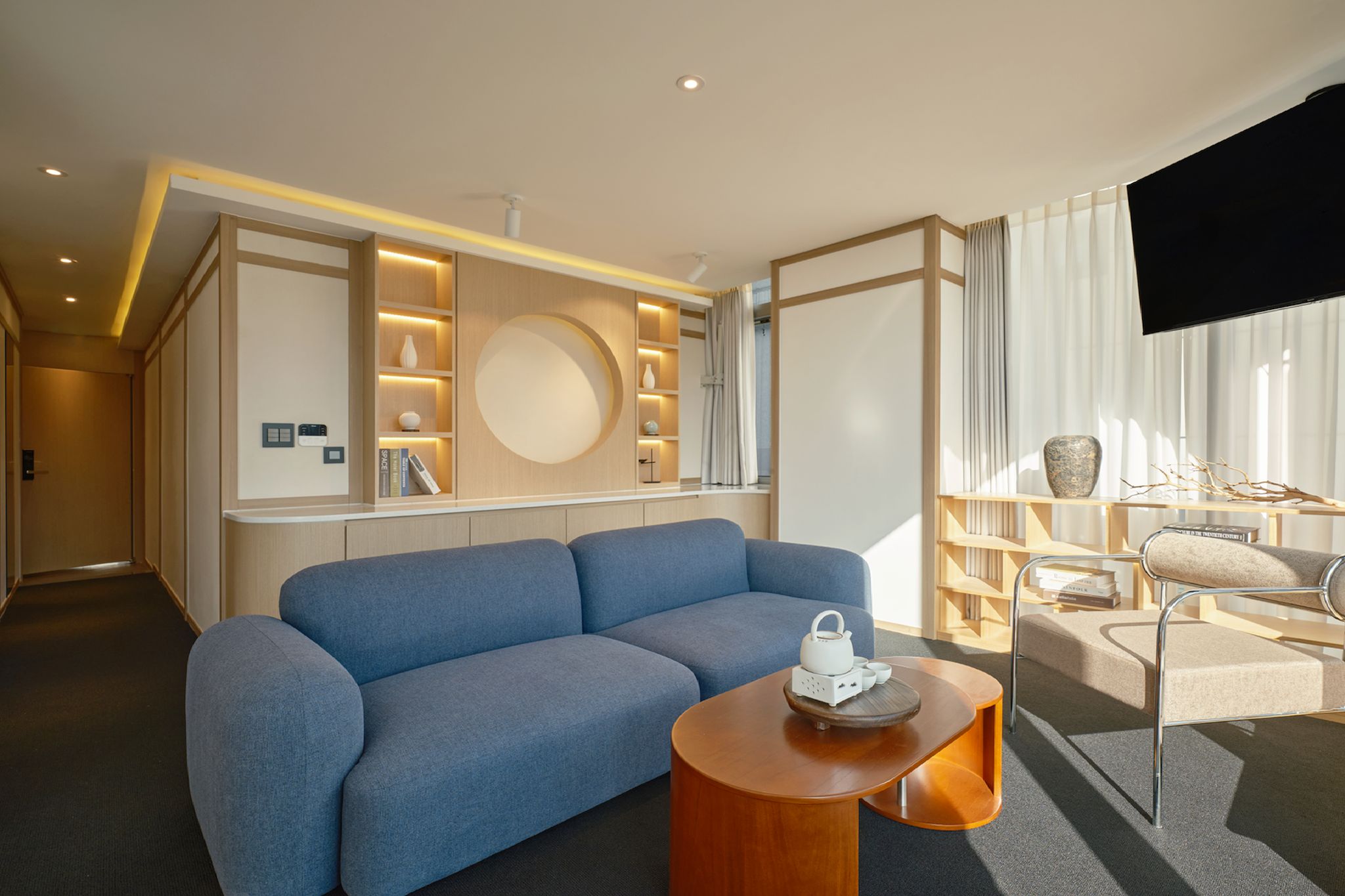 A modern living room with a blue sofa, a wooden coffee table, and a TV on a wall.