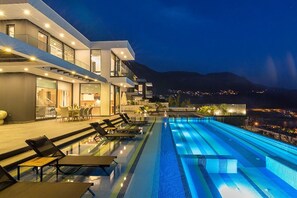 A modern hotel with a rooftop infinity pool, outdoor seating, and a view of the city at night. - Villa Beach House Duo, exclusive 4 bedroom overlooking Kalamar Bay (Antalya)