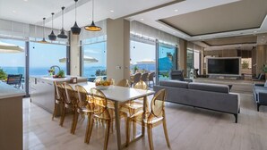 Un amplio salón con una televisión grande, una mesa de comedor con sillas y un sofá.