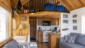 Interior acogedor de una cabaña con sala de estar, cocina y habitación en altillo.