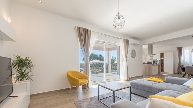 A modern living room with a sofa, a coffee table, and a yellow chair. - Villa Defiance (Benkovac)