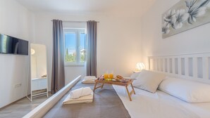 A hotel room with a bed, a bedside table with a tray of breakfast, a TV, a window with curtains, and a painting on the wall. - Villa Defiance (Benkovac)
