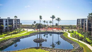 A resort with a central water feature, palm trees, and a view of the ocean.