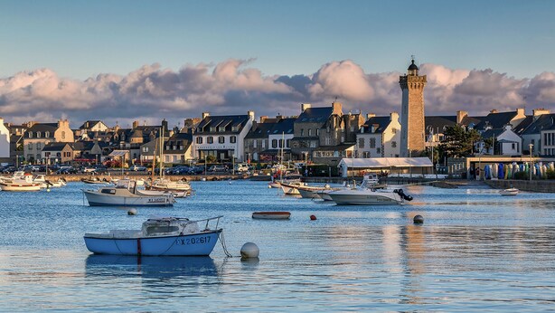 Un port avec des bateaux, une tour imposante et des bâtiments le long de la rive.