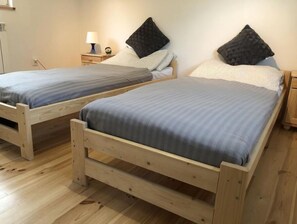 Two comfortable beds with matching headboards and footboards, each with a nightstand and lamp.