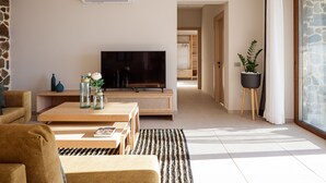 A modern living room with a flat-screen TV, wooden furniture, and a stone accent wall.