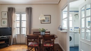 Un comedor con una mesa, sillas, una lámpara y vistas a la cocina.