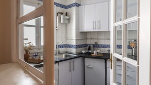 Una cocina con armarios blancos, encimera negra y azulejos decorativos azules.