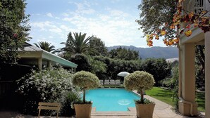 Uma área de piscina com vista para montanhas, rodeada por vegetação exuberante e plantas em vasos.