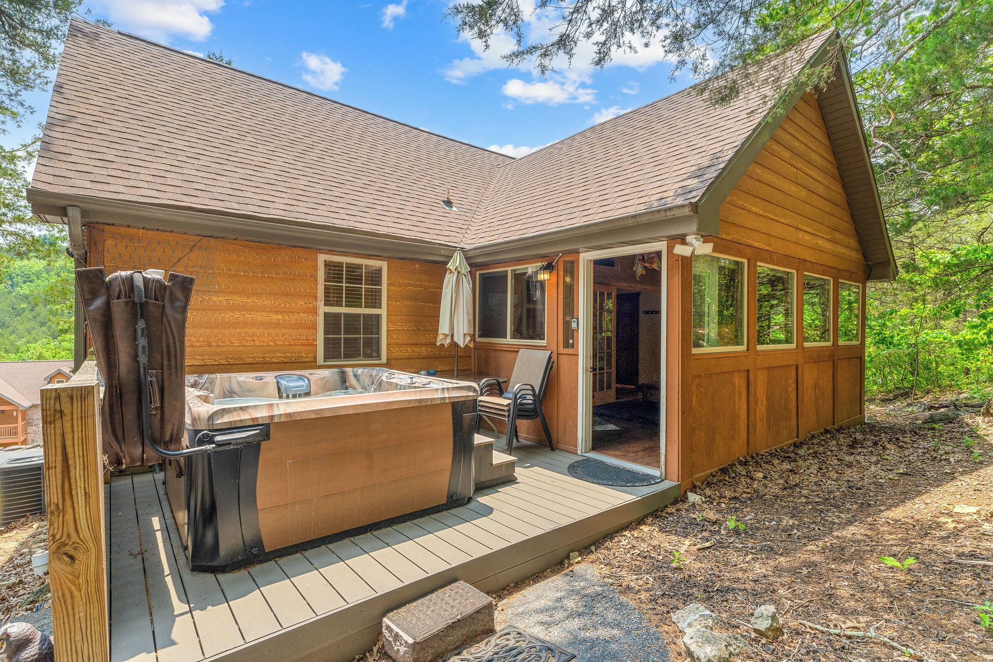 A cabin with a hot tub, deck, and a covered outdoor seating area.