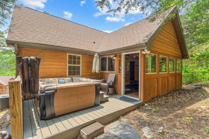 Una cabaña con hidromasaje, terraza y zona de estar exterior cubierta.