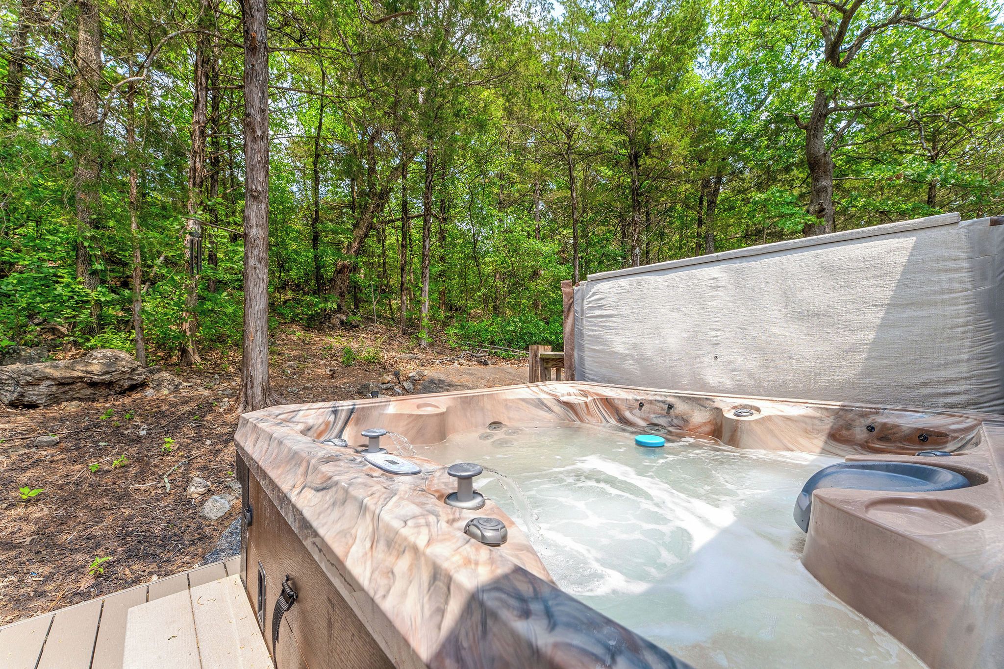 Un bain à remous situé dans une zone boisée, avec une terrasse en bois.