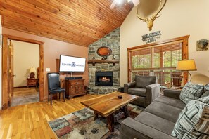 Una sala de estar acogedora con chimenea de piedra, televisión y asientos cómodos.