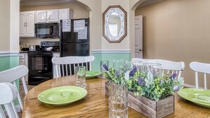 A dining area with a wooden table, green plates, white chairs, and a floral centerpiece. - Ober Hideaway, Hot Tub, WIFI, $560 FREE tickets each paid day!!! (Gatlinburg)