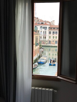 A window view of a narrow canal with boats and buildings. - Hotel Cannaregio 2357 (Venice)