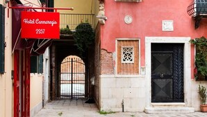 A narrow cobblestone street leading to a building with a red awning and a sign for Hotel Cannaregio 2357. - Hotel Cannaregio 2357 (Venice)