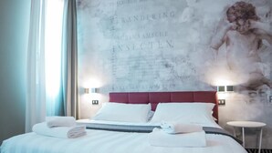 A hotel room with a large bed, two bedside tables, and a wall with a historical painting. - Hotel Cannaregio 2357 (Venice)