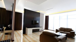 A modern living room with a flat-screen TV, a sofa, and a coffee table. - Grand Karlita Purwokerto (Purwokerto)