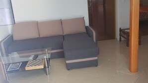 Ein Wohnzimmer mit Ecksofa, Glastisch und einem Schachspiel.
