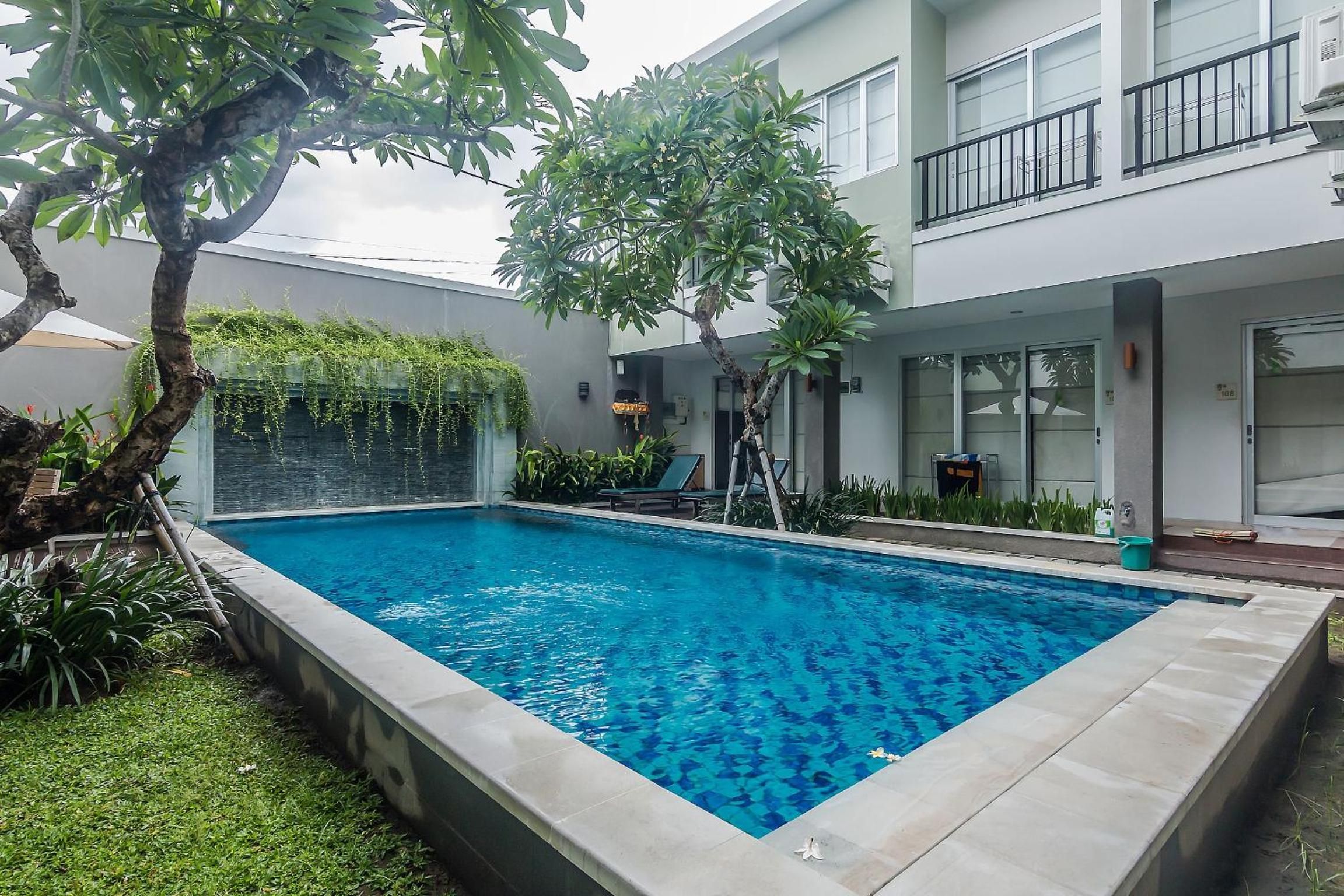 A rectangular swimming pool with clear blue water, surrounded by a low stone wall.