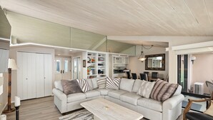A modern living room with a sectional sofa, a coffee table, and built-in shelving. - Sea For Miles Top Floor Oceanfront Rental - A/C, Beach Access, Pool (Solana Beach)