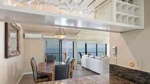 A modern dining area with a marble countertop, wicker chairs, and a view of the ocean. - Sea For Miles Top Floor Oceanfront Rental - A/C, Beach Access, Pool (Solana Beach)