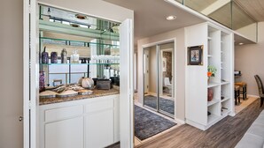 A modern kitchen with a glass-fronted island, white cabinetry, and a built-in seating area with a cushioned bench and a small table. - Sea For Miles Top Floor Oceanfront Rental - A/C, Beach Access, Pool (Solana Beach)