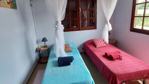 A room with two single beds, each with a canopy, a small bedside table, a lamp, and a window with curtains. - Spacious Creole villa, in the heart of Saint-François (SAINT FRANCOIS)