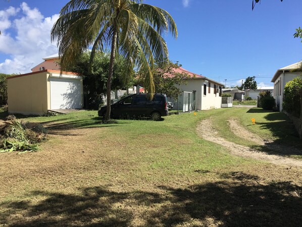 A residential area with houses, a parked car, and a palm tree. - Spacious Creole villa, in the heart of Saint-François (SAINT FRANCOIS)