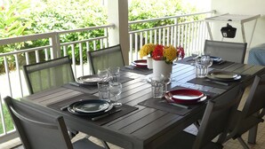 A dining area with a table set for four, chairs, and a vase of flowers. - Spacious Creole villa, in the heart of Saint-François (SAINT FRANCOIS)