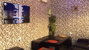 Una habitación moderna con un papel tapiz estampado, un televisor de pantalla plana, una mesa de comedor con taburetes y un sofá.