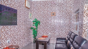 Una habitación con paredes estampadas, un sofá, una mesa con dos platos rojos y una planta decorativa verde.