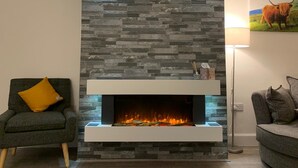 Una sala moderna con chimenea de piedra, cabeza de ciervo montada y un cuadro de vaca.