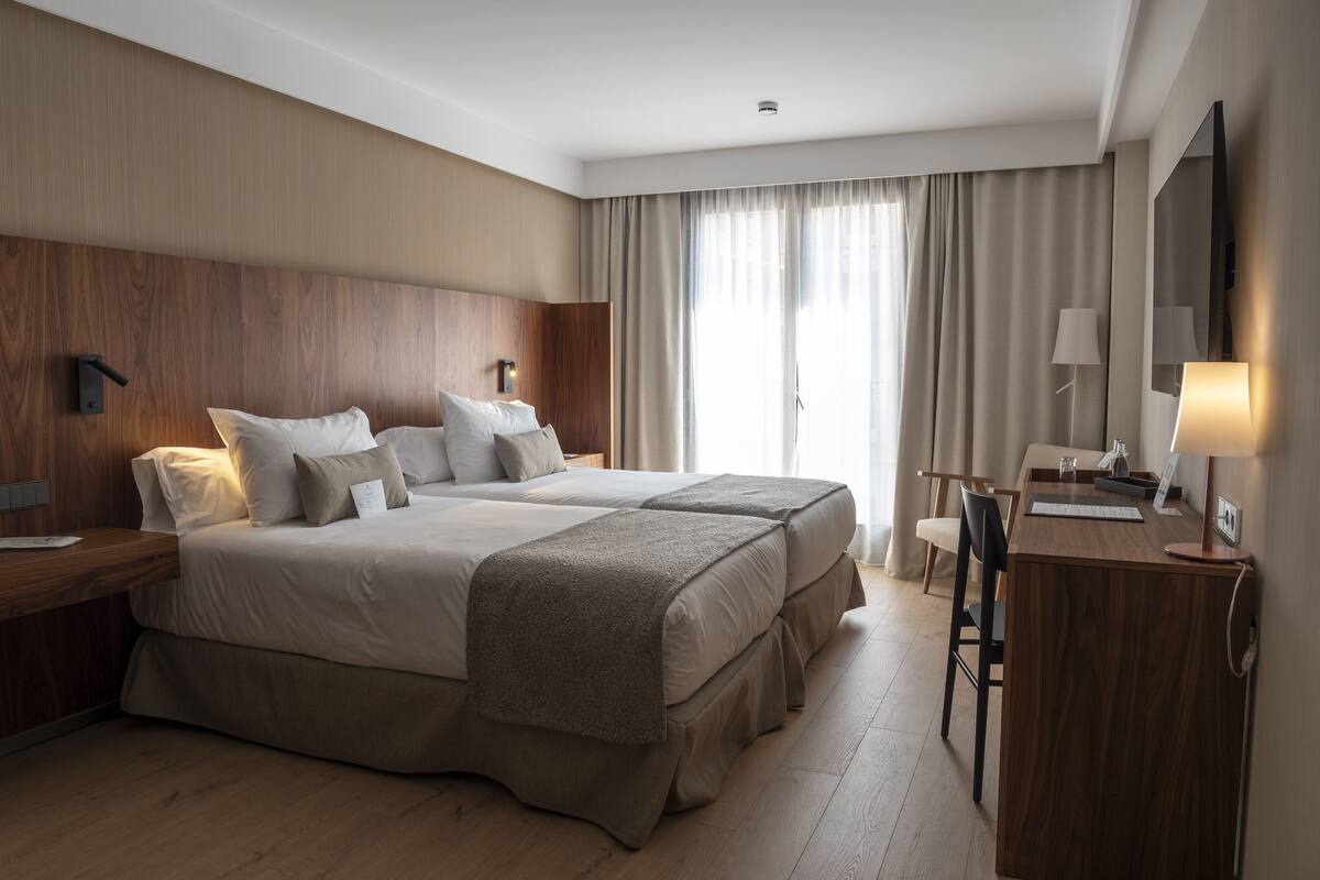 Una habitación de hotel moderna con una cama grande, un escritorio y una silla.