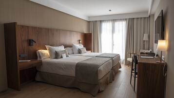 Ein modernes Hotelzimmer mit einem großen Bett, einem Schreibtisch und einem Sessel.