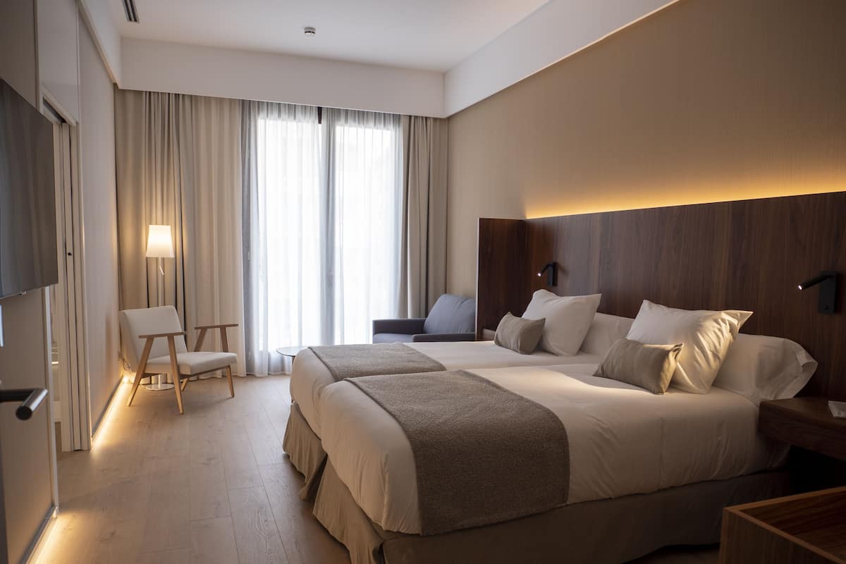 Habitación de hotel con una cama grande, un escritorio, una silla y un televisor.