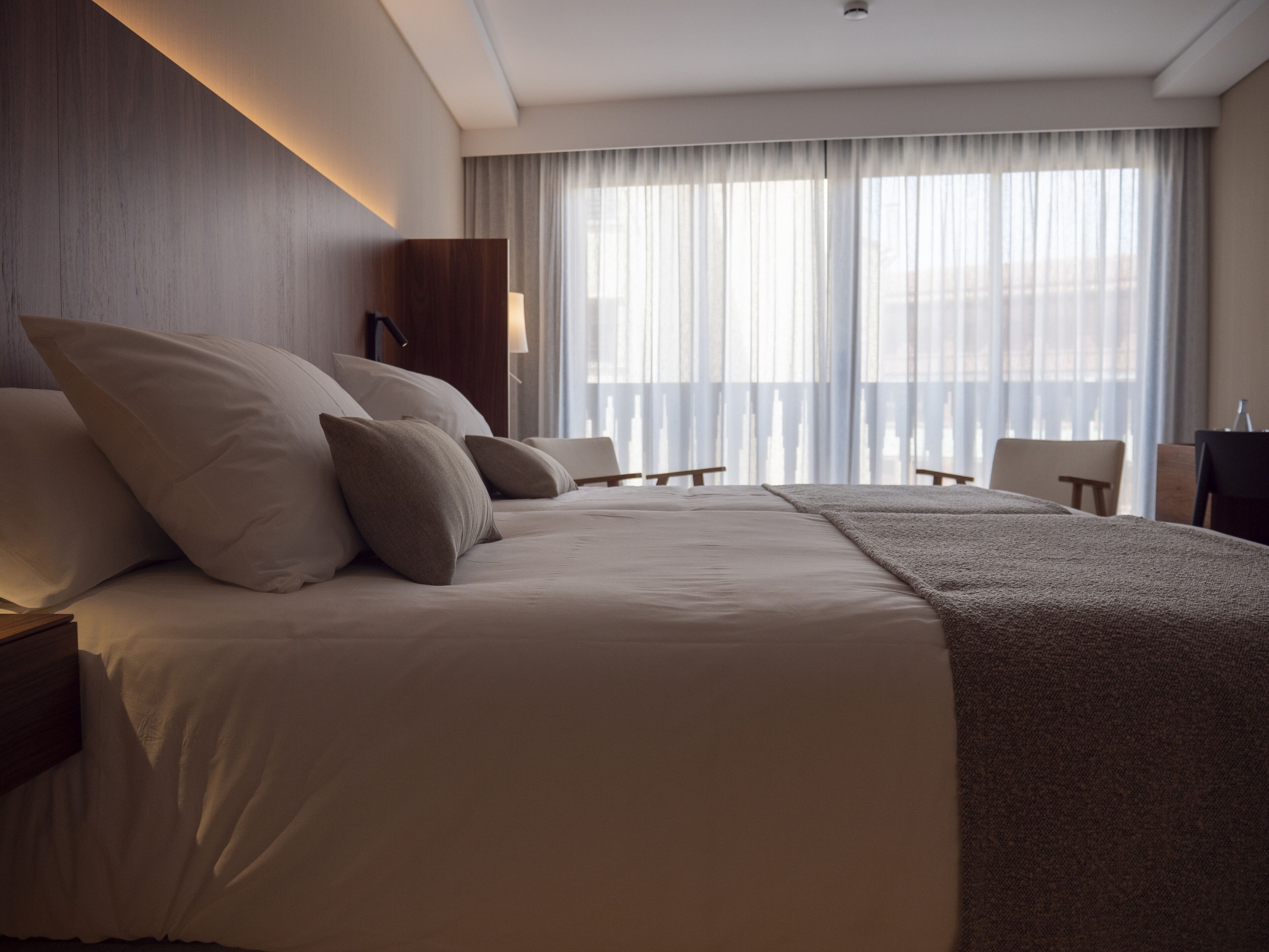 A hotel room with a large bed, a desk, and a chair.