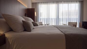 A hotel room with a large bed, a desk, and a chair.