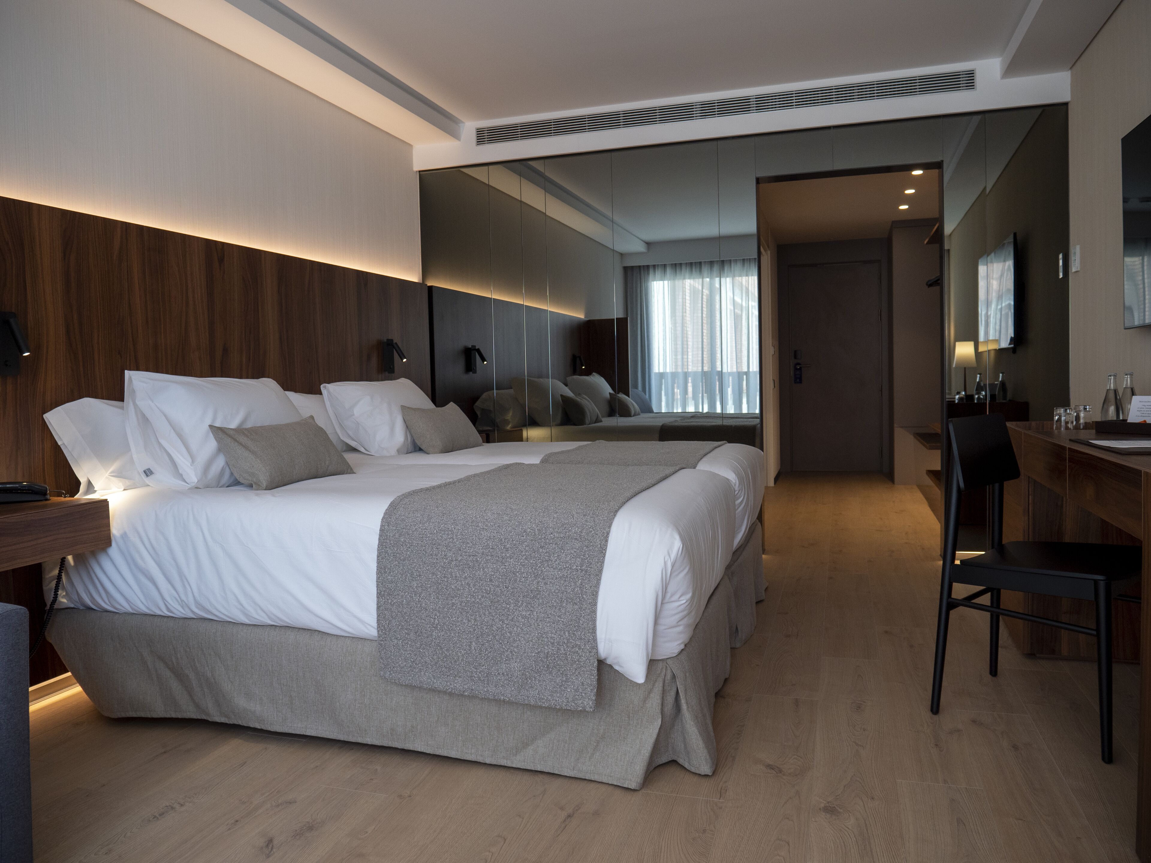 Une chambre d’hôtel moderne avec un grand lit, un bureau et un miroir.
