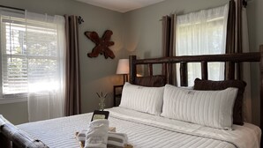 Una cama bien hecha con una colcha blanca acolchada, un cabecero de madera y una mesita de noche con una lámpara.