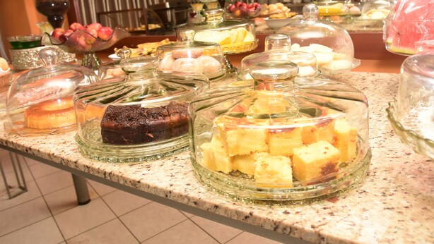 Un buffet con diversi piatti coperchiati, tra cui torte e pasticcini.