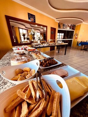 A buffet setup with various food items and a seating area. - Serra Azul Plaza Hotel (Barra do Garcas)