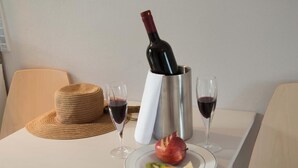Een tafel met een fles wijn, twee glazen, een hoed en een bord met fruit.