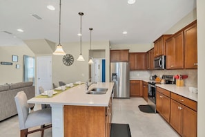 A modern kitchen with wooden cabinets, stainless steel appliances, and pendant lighting.