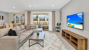 Een moderne woonkamer met een grote flatscreen televisie, een bank, een salontafel en een tv-meubel.