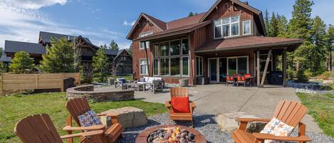 Relax by the fire pit in a serene outdoor space surrounded by Adirondack chairs and lush greenery.