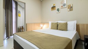A hotel room with a bed, a bedside table, a lamp, and wall art. - Hotel Santa Cruz (Santa Cruz do Sul)