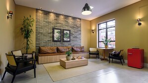 A modern living room with a brick wall, a sofa, a coffee table, and a red refrigerator. - Hotel Santa Cruz (Santa Cruz do Sul)