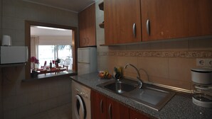 Une cuisine avec des meubles de rangement en bois, un évier en acier inoxydable, un lave-linge et une machine à café.