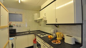 A compact kitchen with white cabinets, a gas stove, a coffee maker, and a toaster. - Welcome to our cozy apartment for rent in Roses, Costa Brava! Just 300 meters from the beautiful Santa Margarita beach. (Roses)